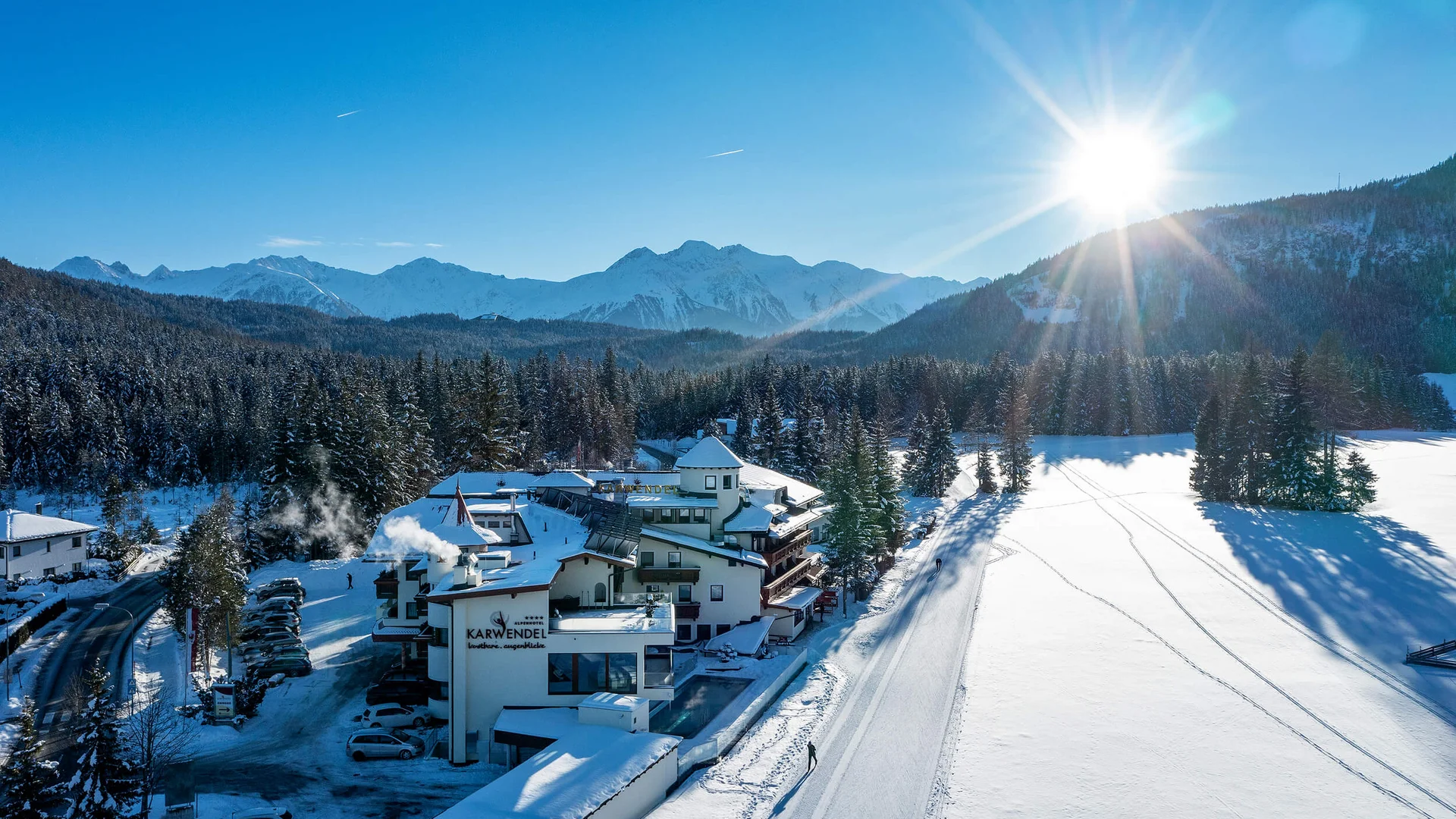 Hotel Karwendel in snowy winter forest with mountains and bright sun