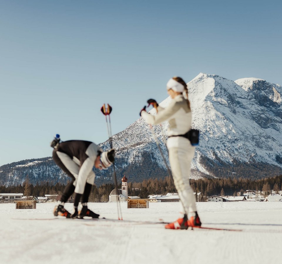 Checkliste für deine Langlaufvorbereitung © Alex Moling Zwei Langläufer auf verschneiter Loipe vor Alpenpanorama