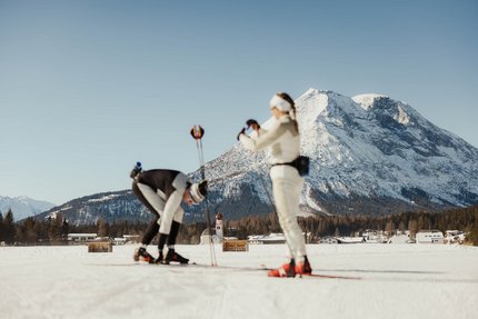 Zwei Langläufer auf verschneiter Loipe vor Alpenpanorama