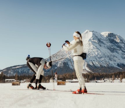 Zwei Langläufer auf verschneiter Loipe vor Alpenpanorama