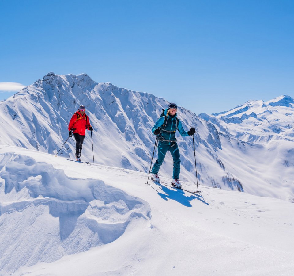 Top 3 Must-Glide Skitouren im Großarltal © TVB Großarltal / Peter Maier Zwei Skitourengeher in bunten Outfits wandern im sonnigen, verschneiten Gebirge