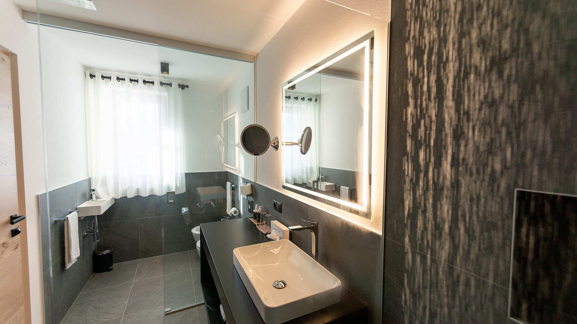 Modernes Badezimmer mit beleuchtetem Spiegel und Waschbecken