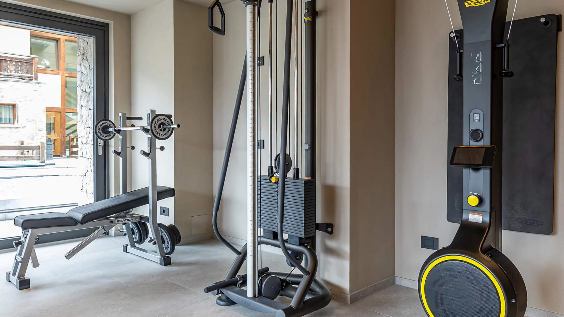 Modern gym room with various workout machines and weight bench