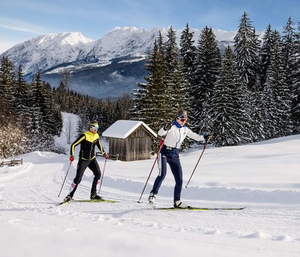5 Tipps für Langlaufurlaub im Ausseerland © TVB Ausseerland - Salzkammergut / Katrin Kerschbaumer Zwei Langläufer in Winterlandschaft mit schneebedeckten Bäumen und Bergen