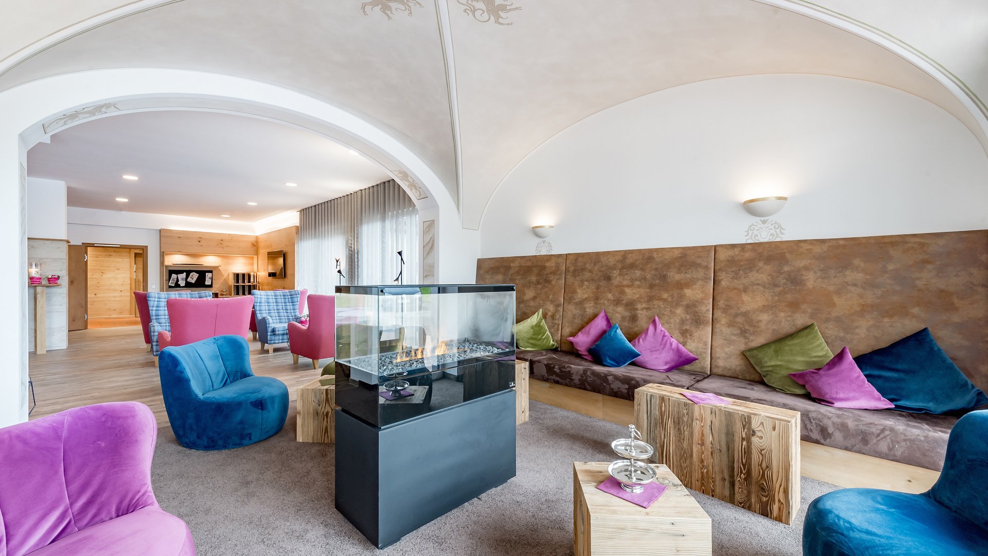 Cozy lounge with colorful chairs, fireplace, and wooden tables