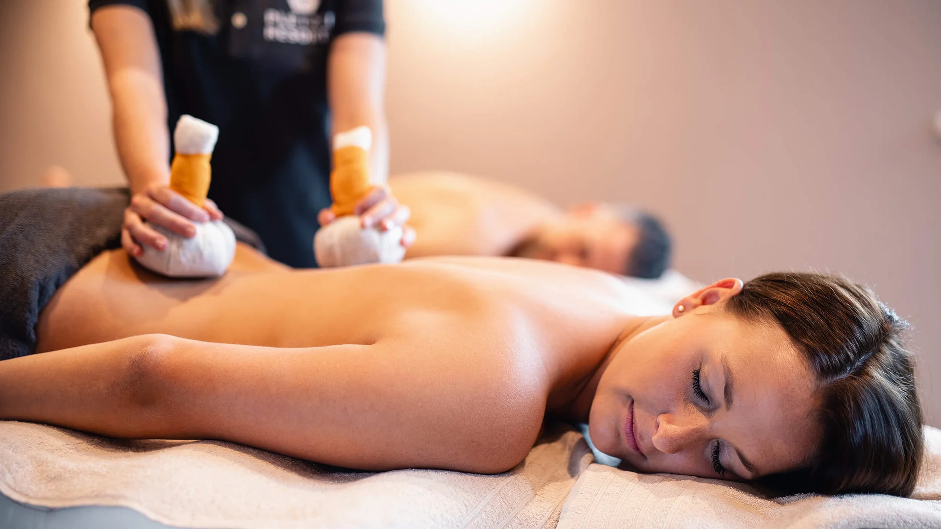 Frau erhält Kräuterstempelmassage auf dem Rücken im Spa