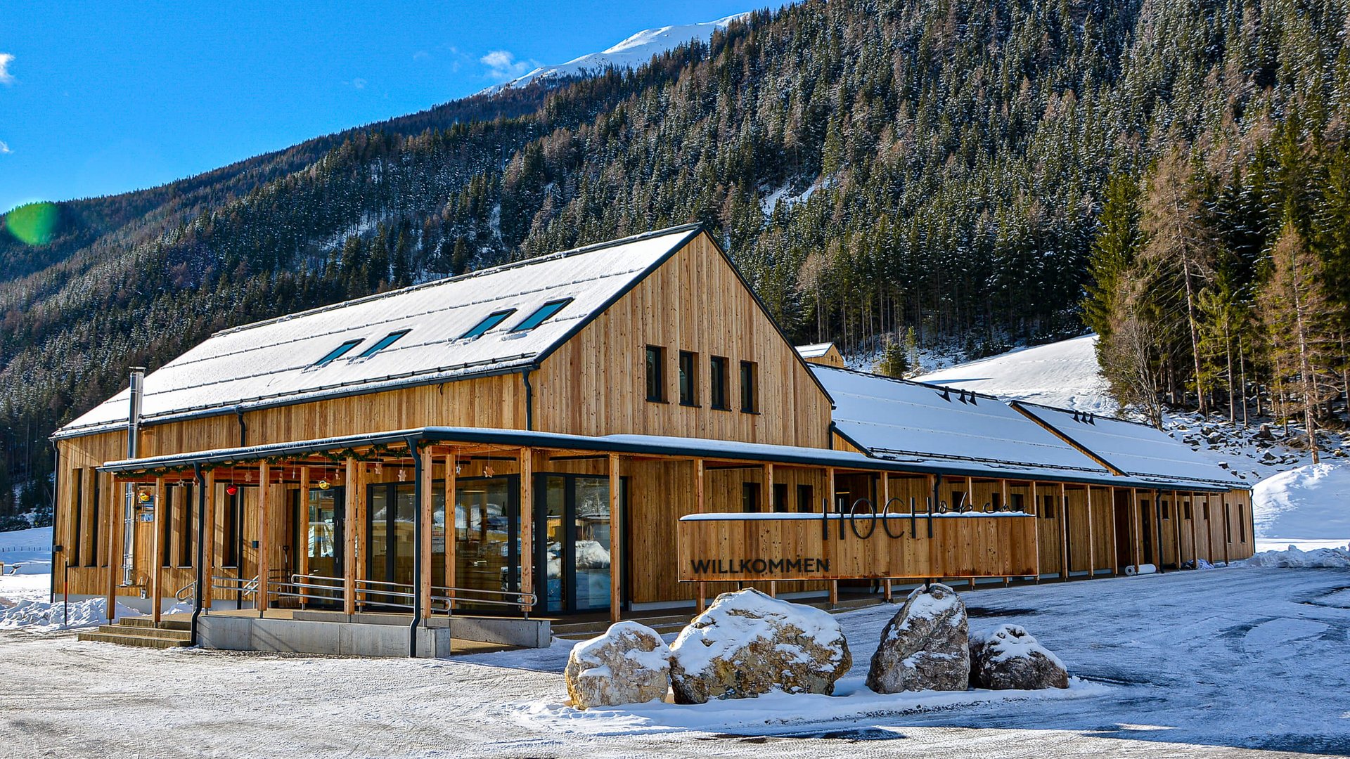 Wooden building in snowy landscape with forested mountain behind