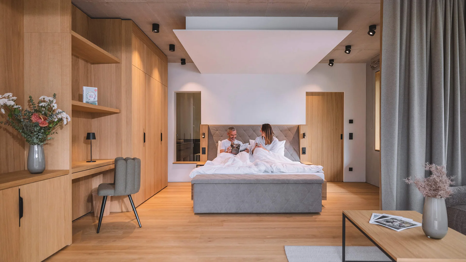 Paar im modernen Schlafzimmer mit Holzdesign und grauem Bett