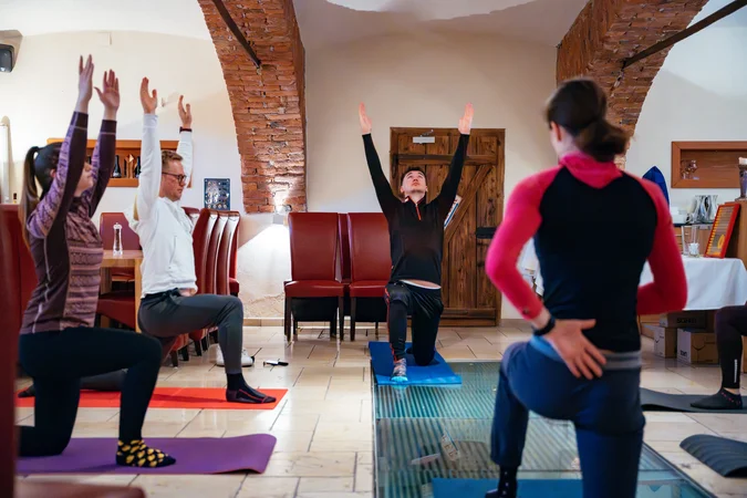 Gruppe übt Yoga in einem Raum mit Backsteinbögen und Matten auf dem Boden
