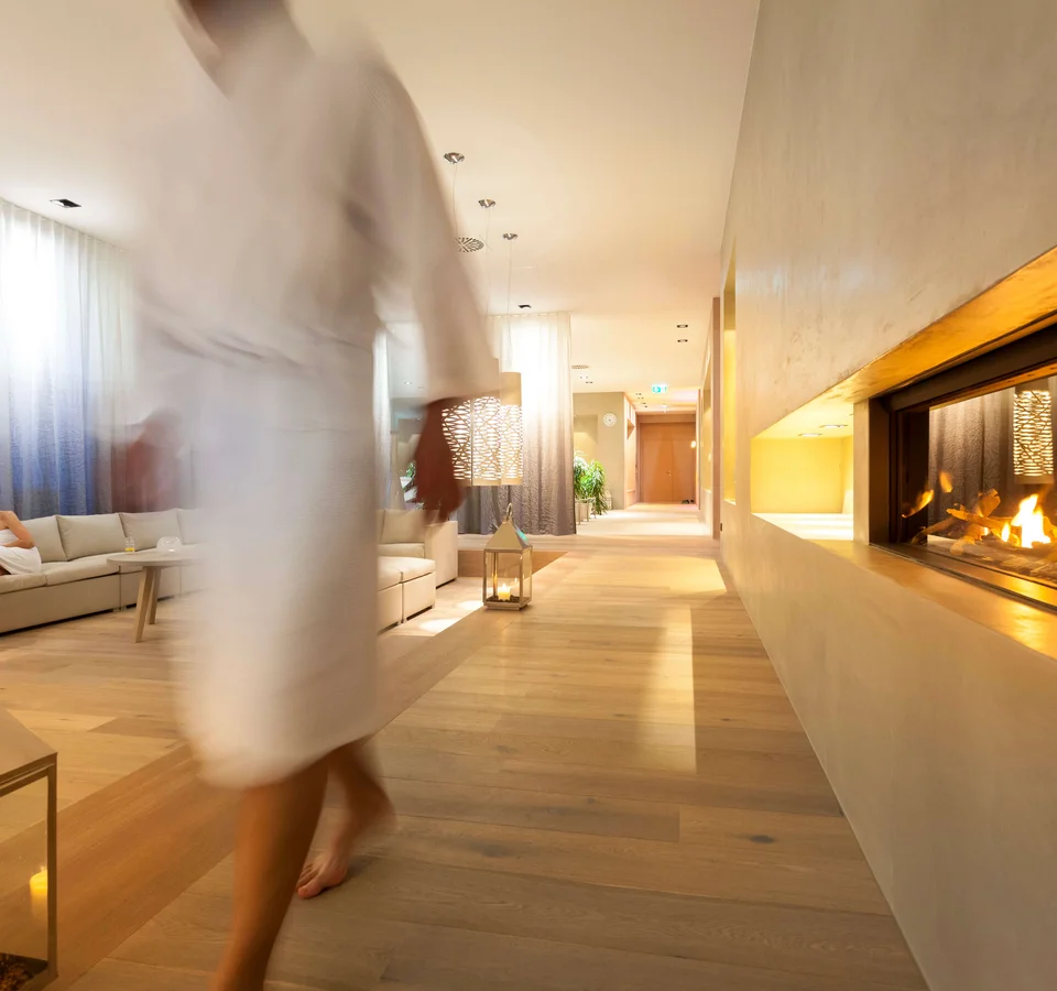 Gemütliche Hotellounge mit Kamin, Sofa und einer Frau im Vordergrund