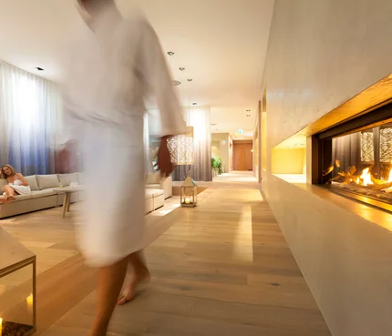 Gemütliche Hotellounge mit Kamin, Sofa und einer Frau im Vordergrund