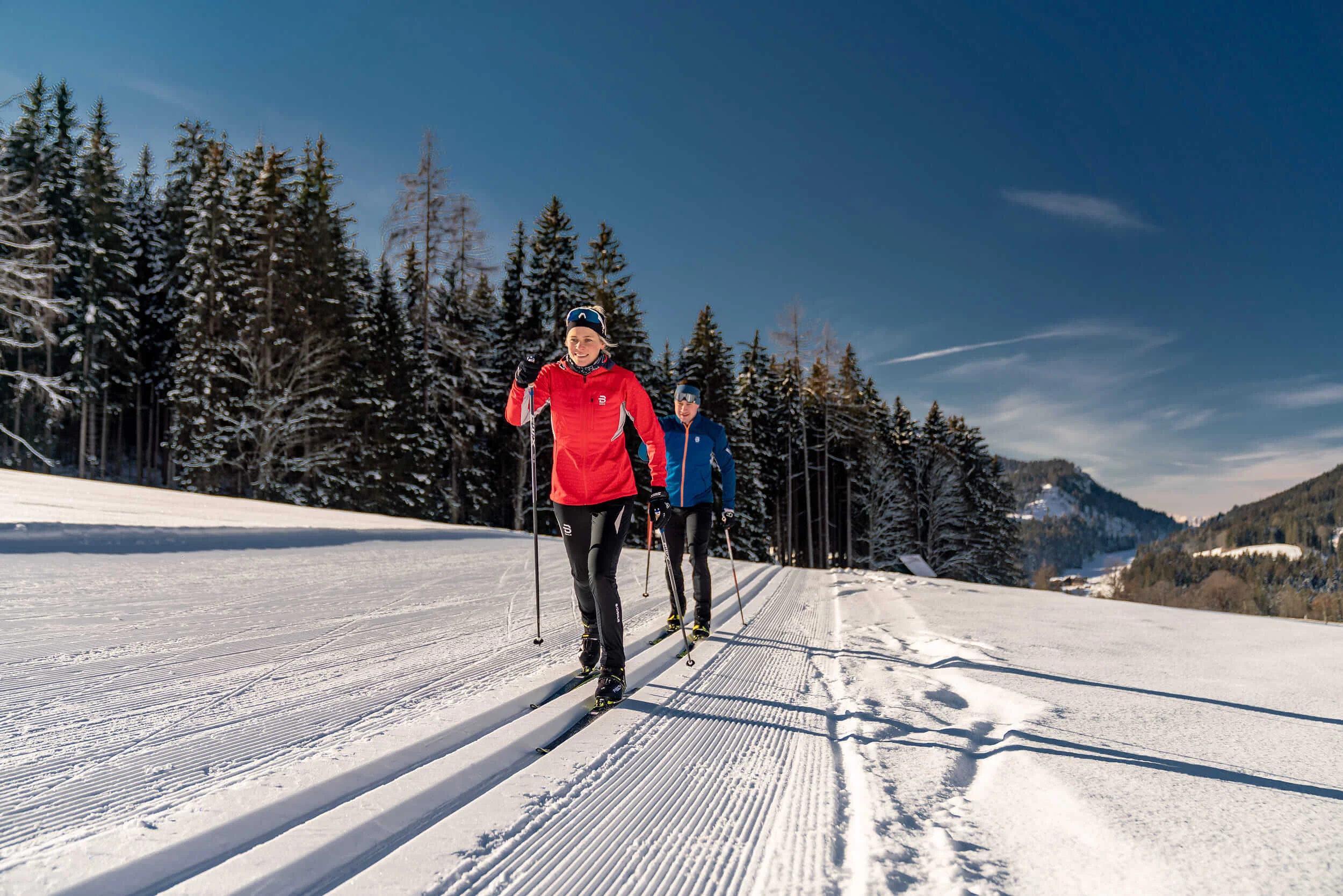 Schneesicher langlaufen: Wo Snowfarming in Österreich frühen Saisonstart möglich macht
© TVB Schladming Dachstein - Christine Höflehner Zwei Menschen Langlaufen auf einer sonnigen, verschneiten Loipe mit Wald im Hintergrund