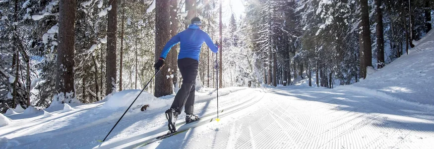 Winterurlaub in Vorarlberg © Dominik Berchtold Langläufer auf einer verschneiten Loipe im Wald