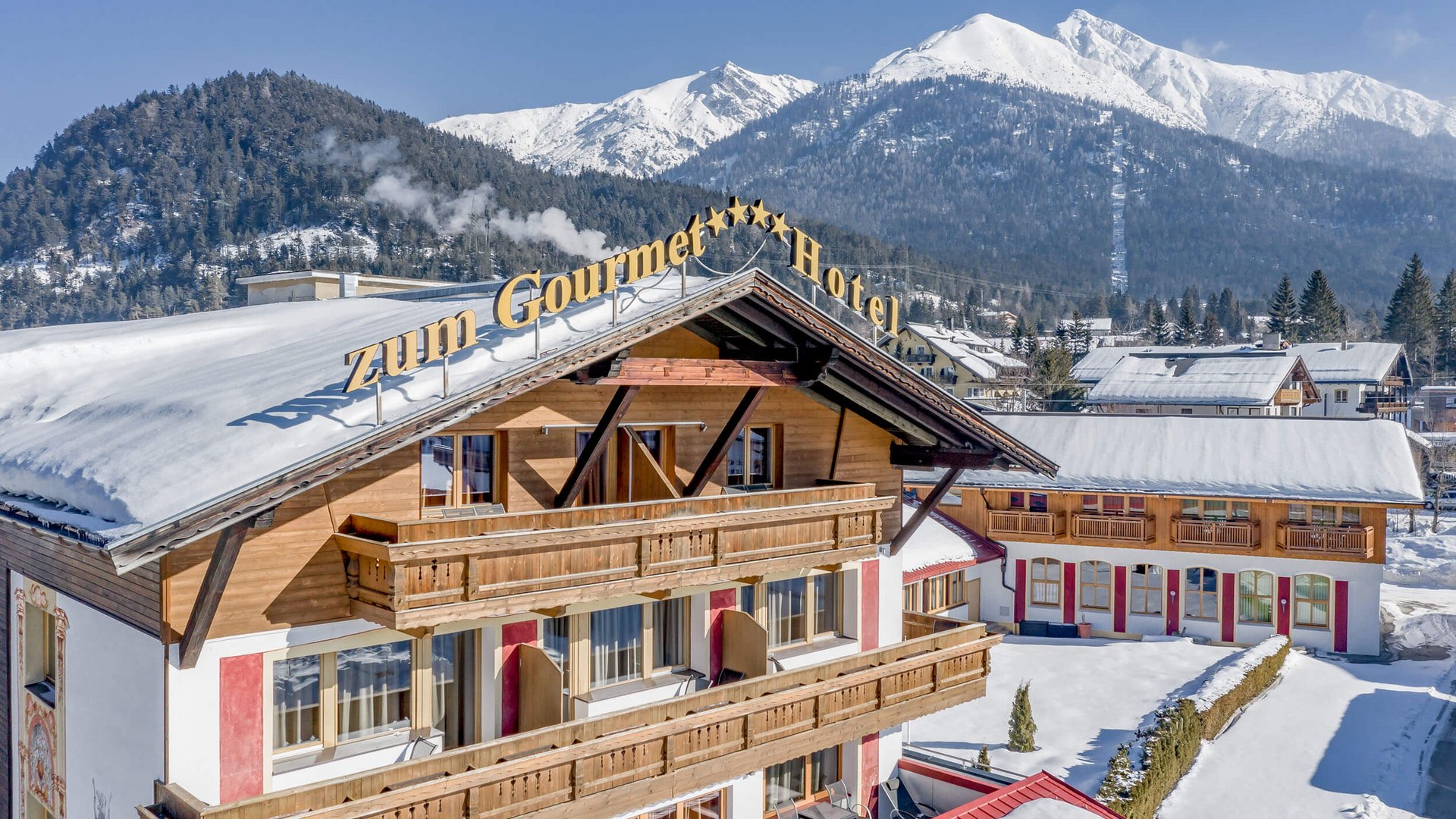 Zum Gourmet hotel in snowy mountain village with Alpine backdrop