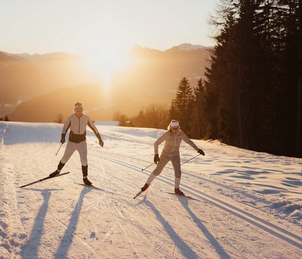 Zwei Langläufer im Sonnenuntergang auf verschneiter Strecke