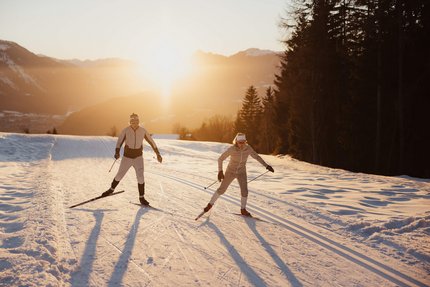 Zwei Langläufer im Sonnenuntergang auf verschneiter Strecke