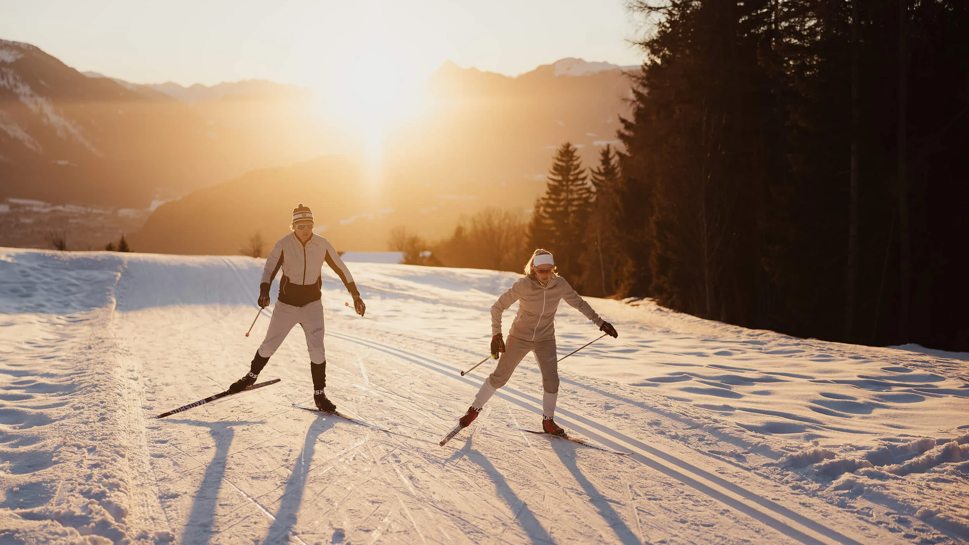 Zwei Langläufer im Sonnenuntergang auf verschneiter Strecke