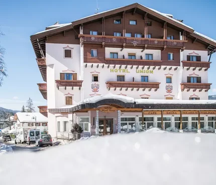Hotel Union im Schnee mit Skifahrern und klarem Himmel