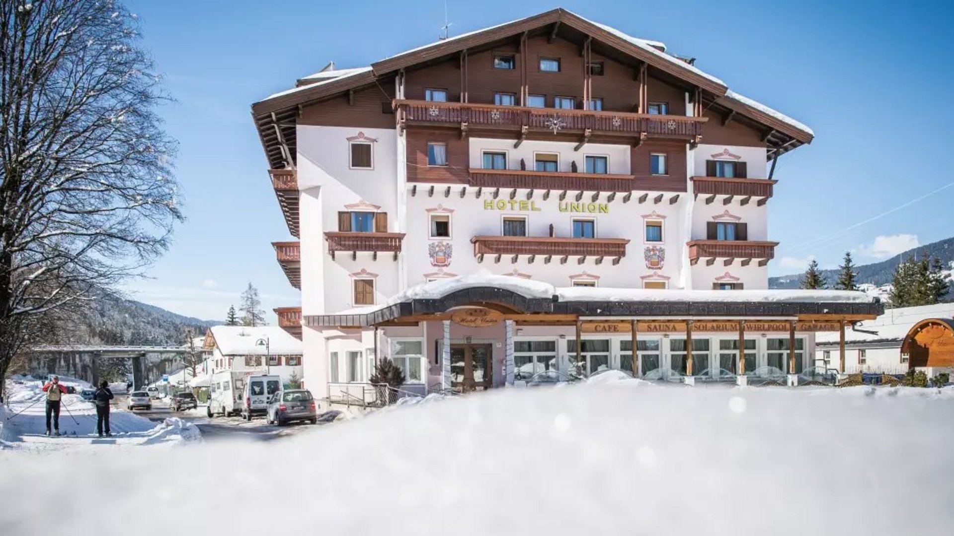 Hotel Union im Schnee mit Skifahrern und klarem Himmel
