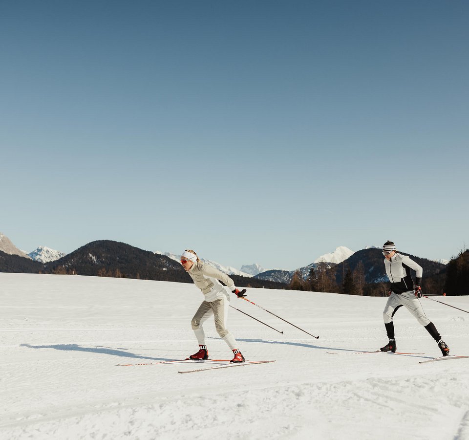 Best of Seefeld © Alex Moling Zwei Personen beim Langlaufen auf schneebedecktem Feld vor Bergen