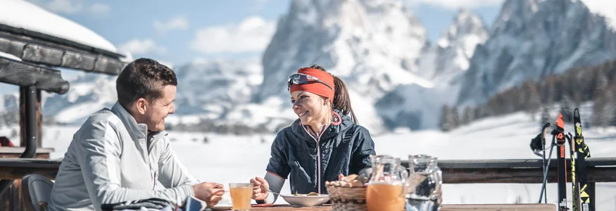 Couple having breakfast outdoors with snowy mountains in the background