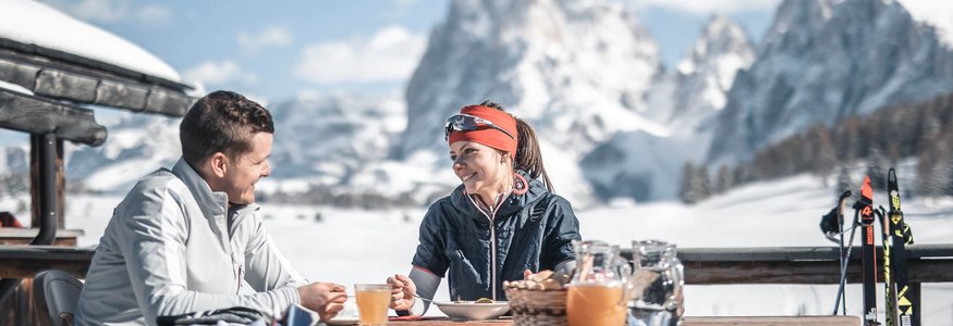Paar beim Frühstück im Freien mit Schneelandschaft und Bergen im Hintergrund