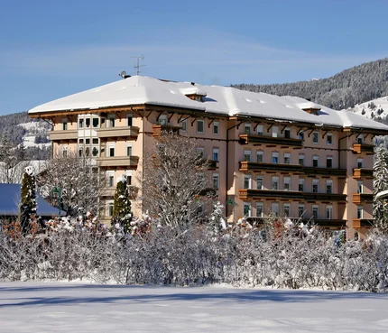 Großes Hotel in verschneiter Winterlandschaft mit Bergen im Hintergrund