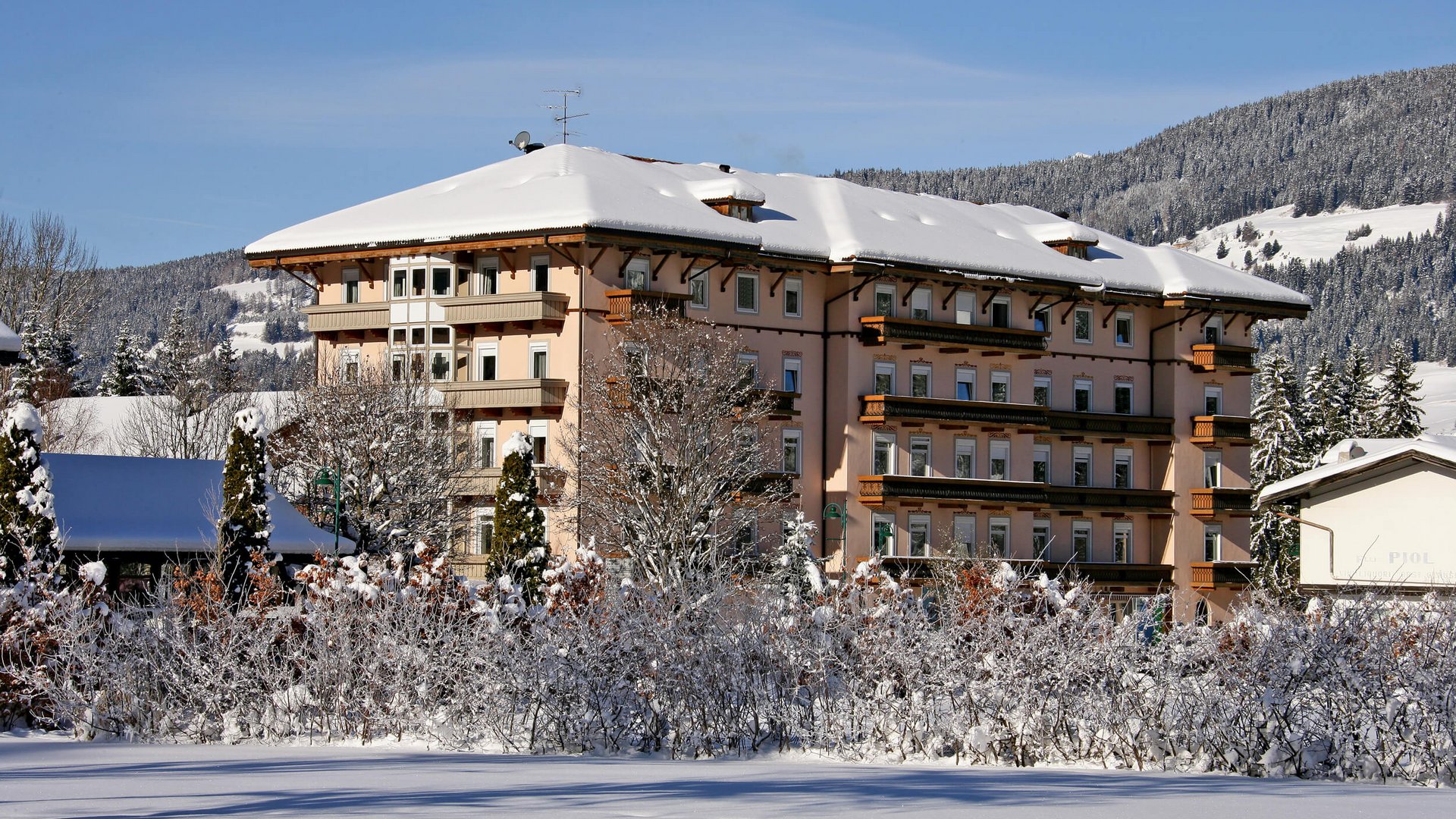 Großes Hotel in verschneiter Winterlandschaft mit Bergen im Hintergrund