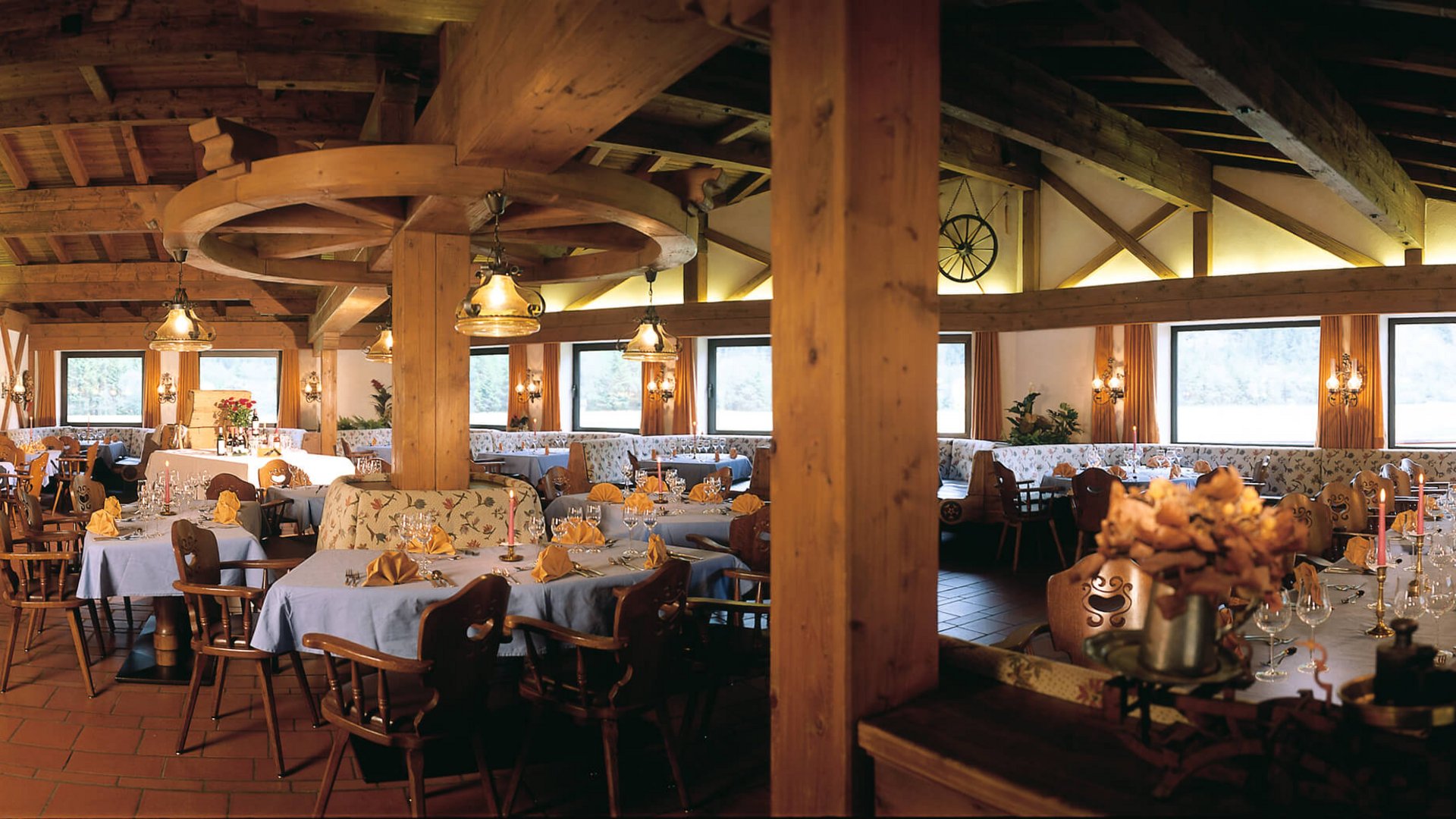 Cozy restaurant with wooden furniture and tables set with orange napkins
