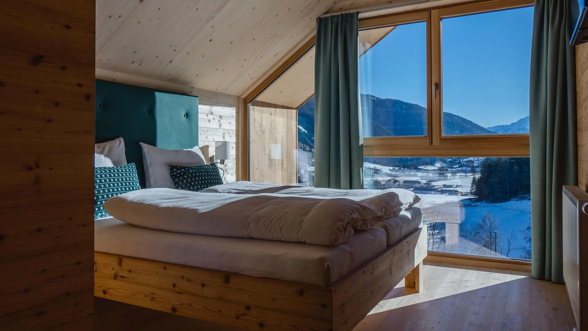 Schlafzimmer mit Holzmöbeln und Bergblick durch großes Fenster