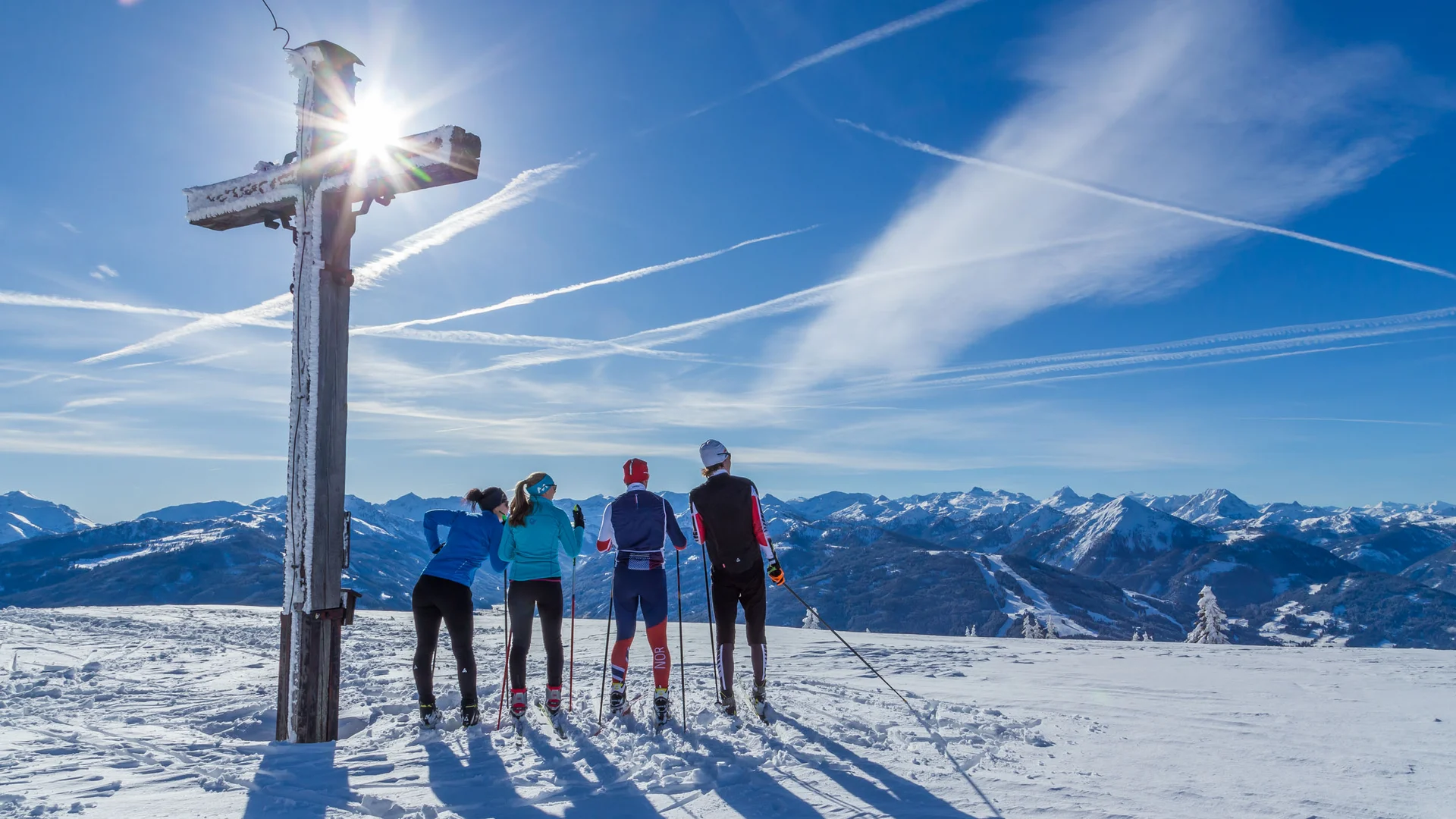 Bauernhof Krahlehen © Coen Weesjes Four cross-country skiers by a summit cross on a sunny winter day in the mountains