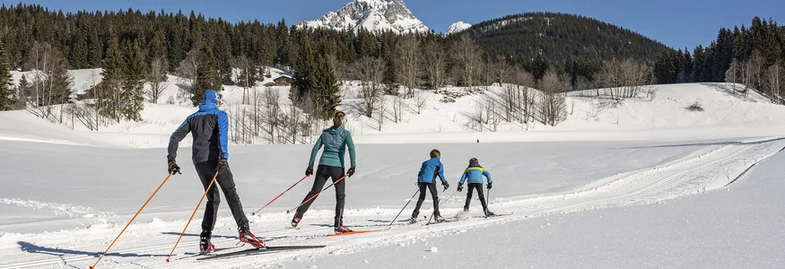 9 Gründe für Langlaufurlaub in Filzmoos © Lorenz Masser - Filzmoos Tourismus Vier Personen beim Langlaufen in verschneiter Berglandschaft bei klarem Himmel