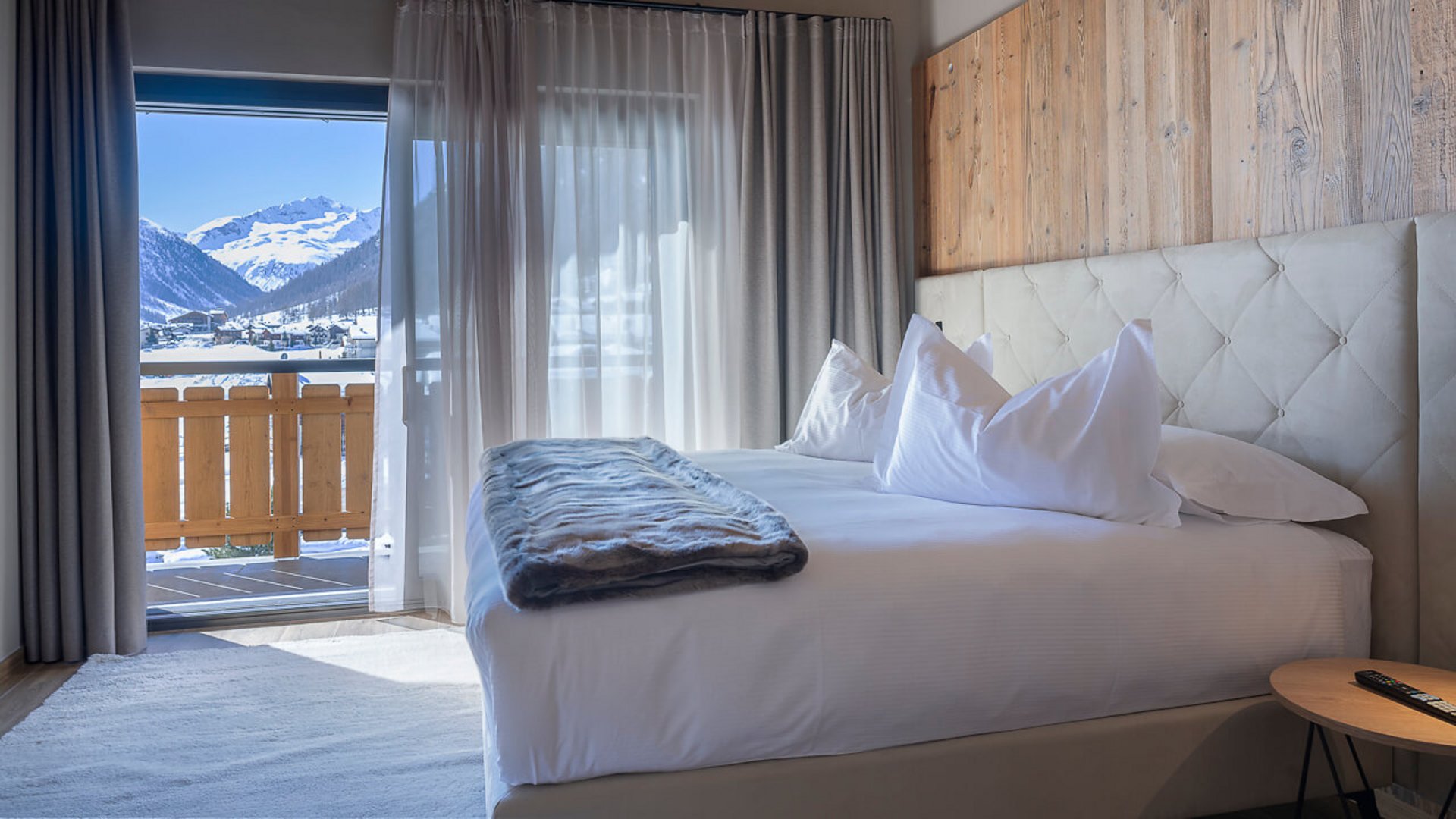 Modernes Hotelzimmer mit Bett und Bergblick durch Glasschiebetür