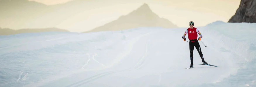 Schladming-Dachstein Langläufer auf schneebedeckter Strecke mit Bergen im Sonnenuntergang