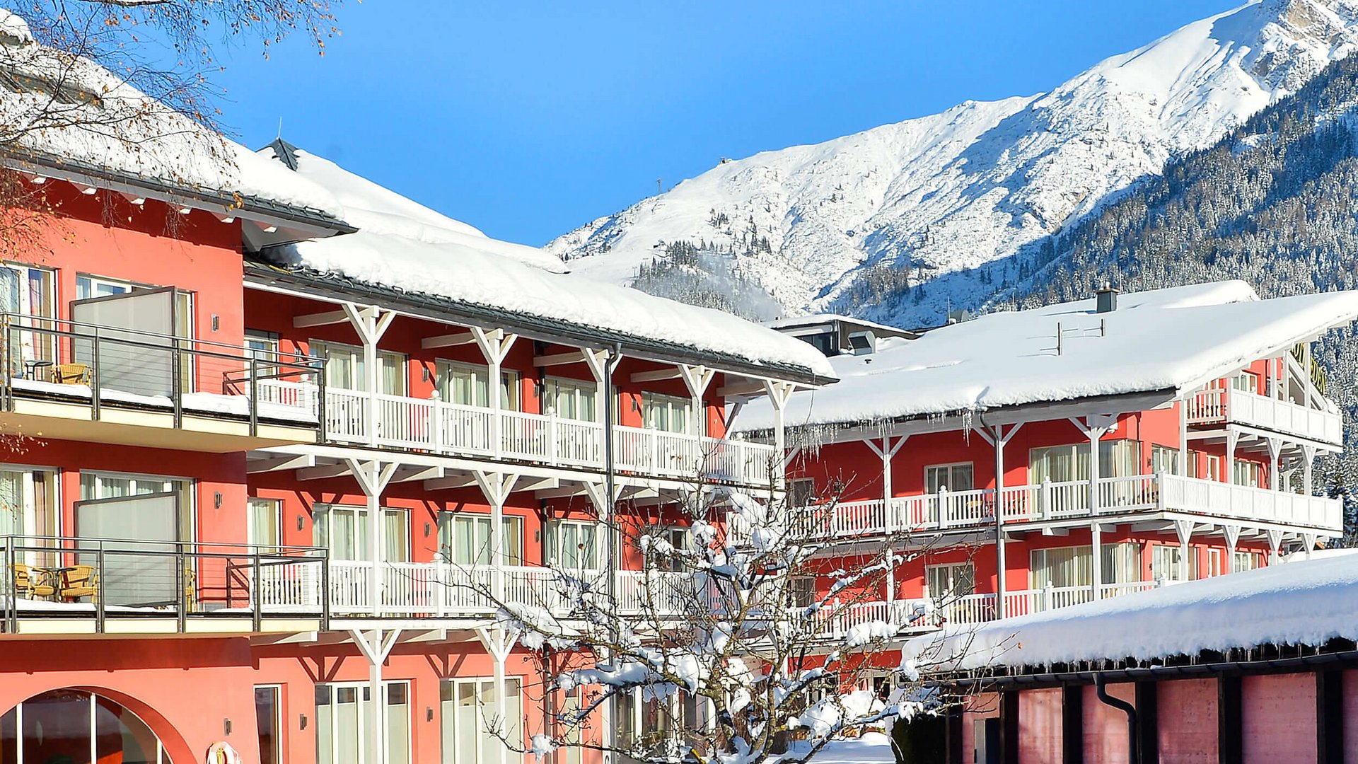 Red buildings covered with snow in front of snowy mountains