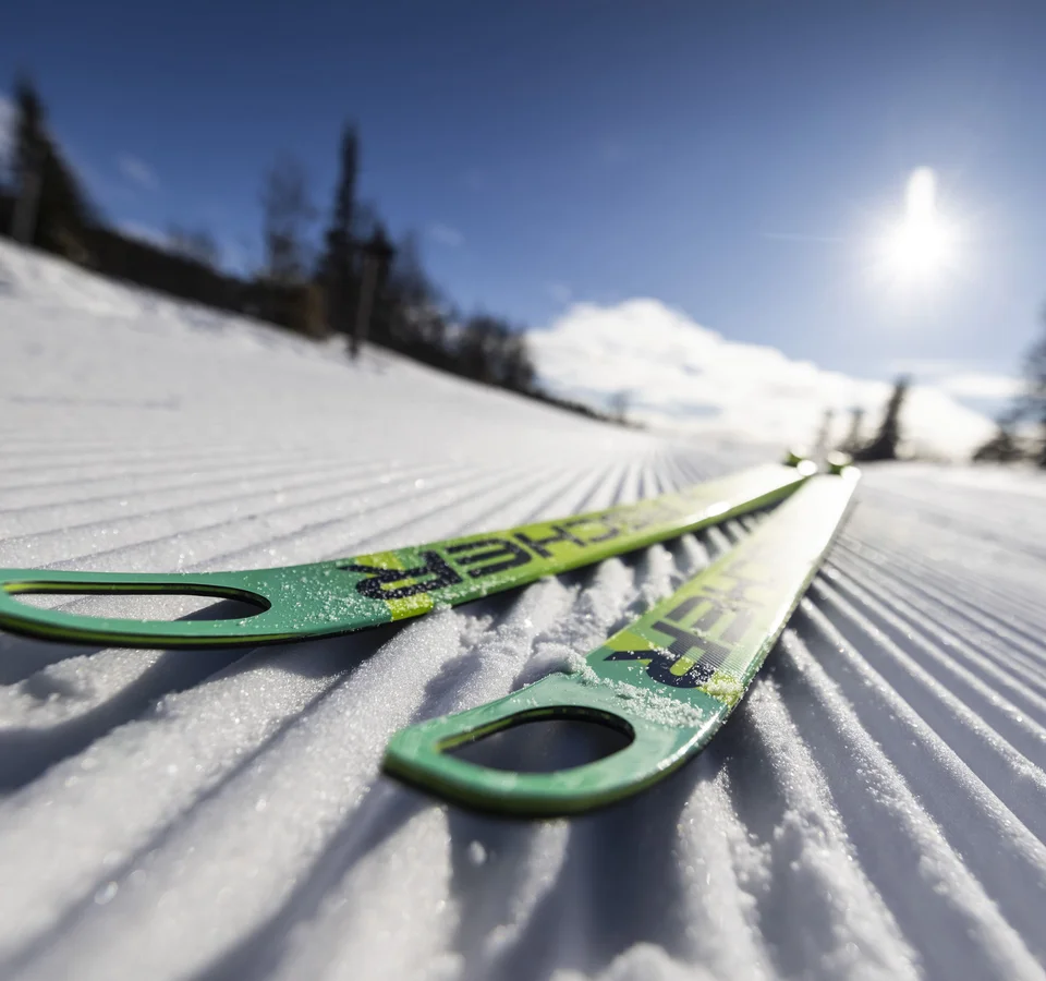 Die richtige Langlaufski-Länge
© Fischer Sports GmbH Grüne Skier liegen auf frisch präparierter Loipe im Sonnenschein