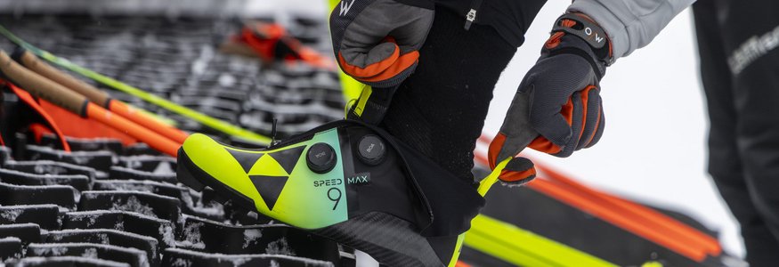 Schneeschuh anziehen auf verschneiter Fläche mit Skistöcken im Hintergrund