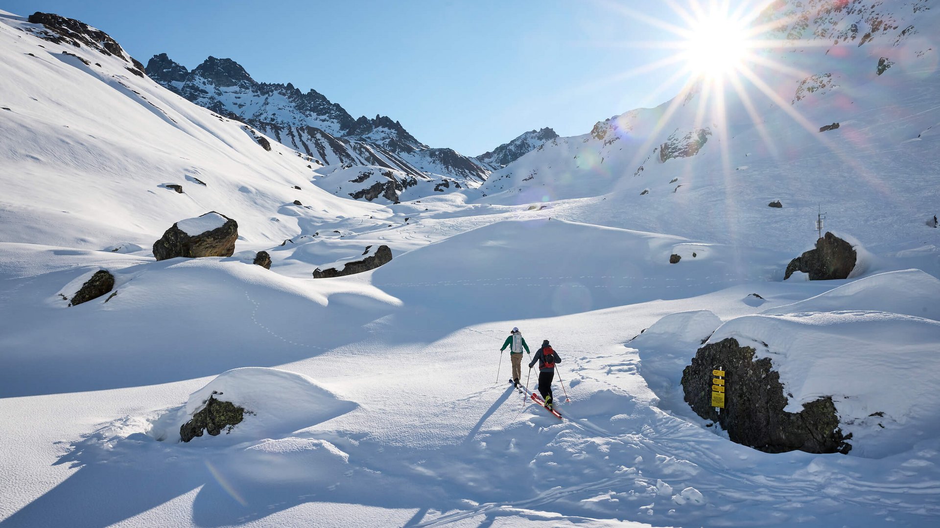 Two skiers hiking in sunny snowy mountain landscape