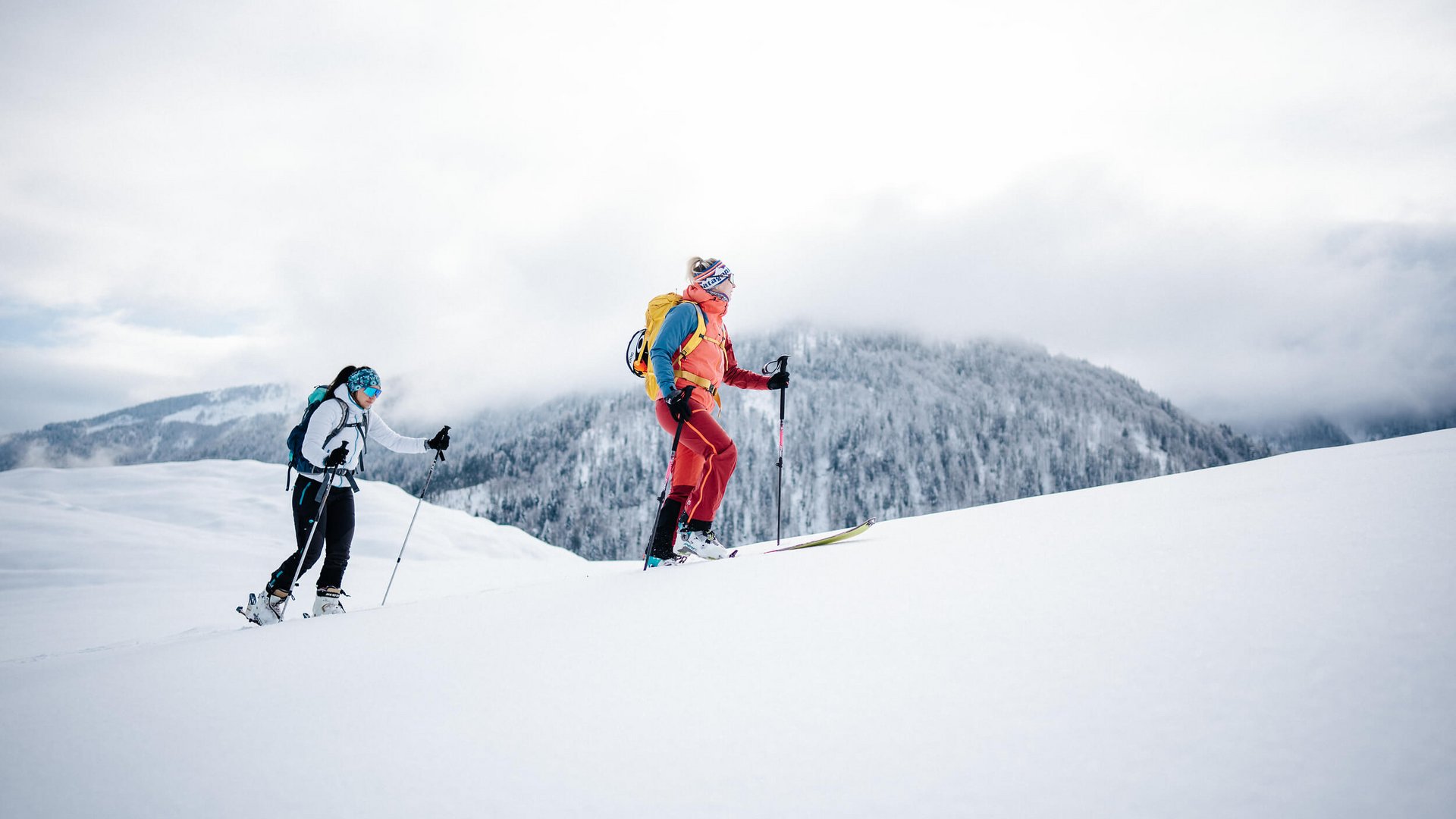 Two skiers hiking in snow with mountain background