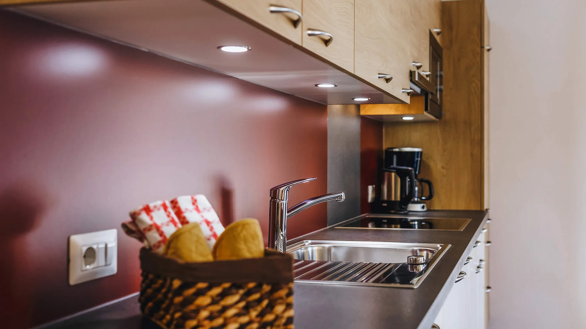 Modern kitchen with sink, stove, coffee maker, and basket on counter