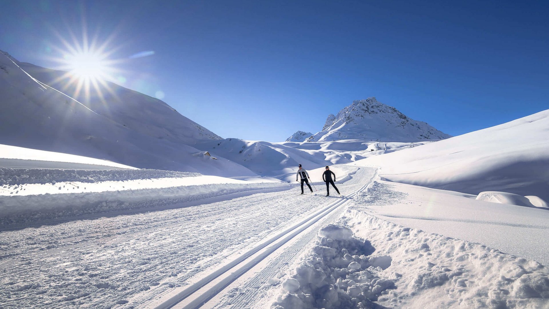 Two skiers on a sunny snow-covered mountain trail