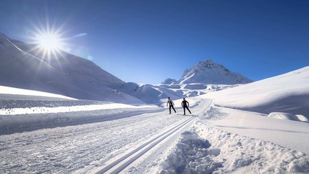 Zwei Skifahrer auf einer sonnigen, verschneiten Bergloipe