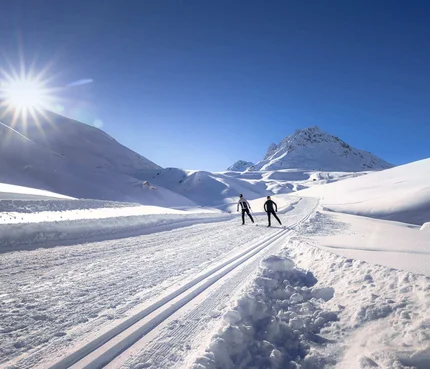 Zwei Skifahrer auf einer sonnigen, verschneiten Bergloipe