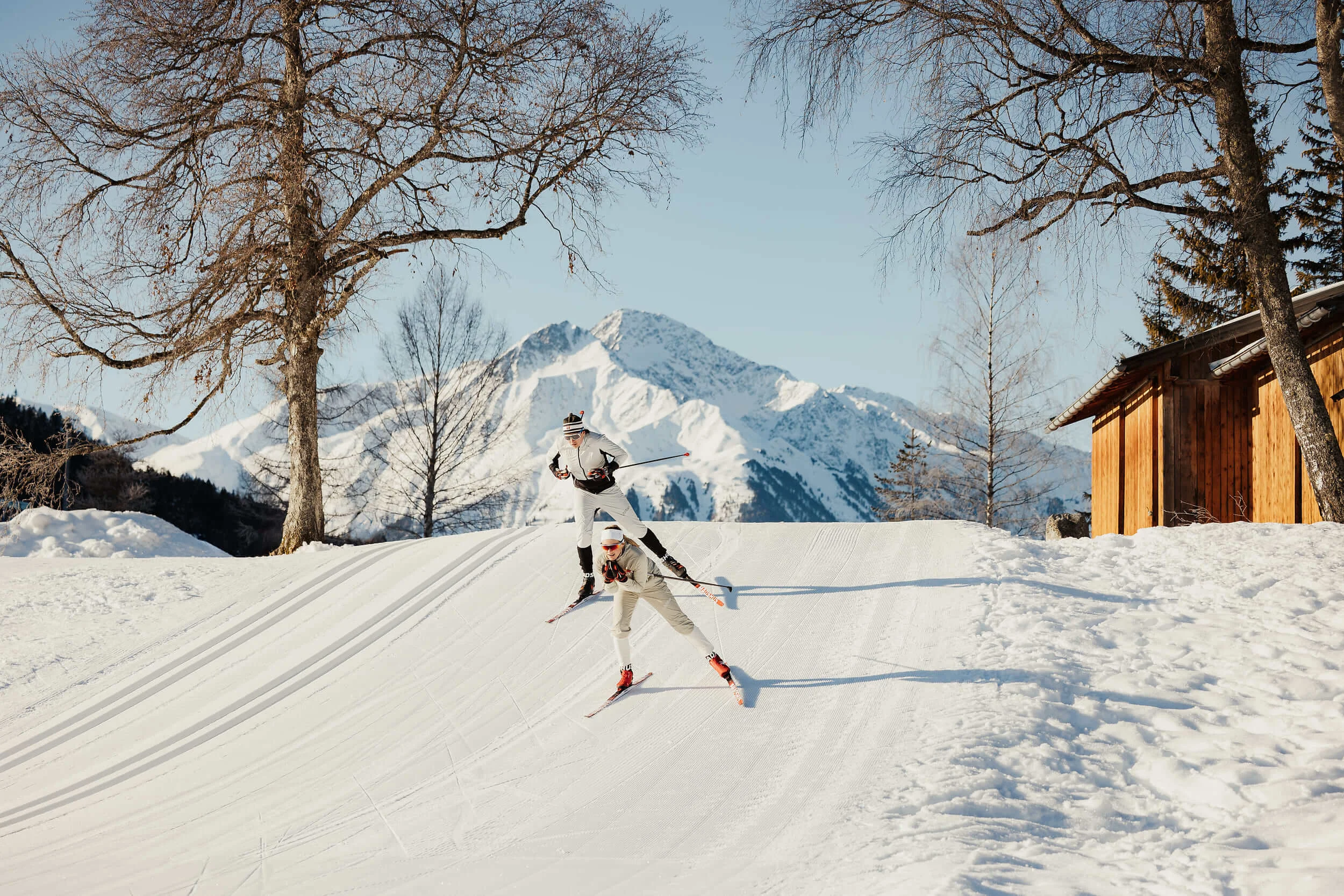 Zwei Langläufer fahren im Winter bei Bergkulisse auf Schnee