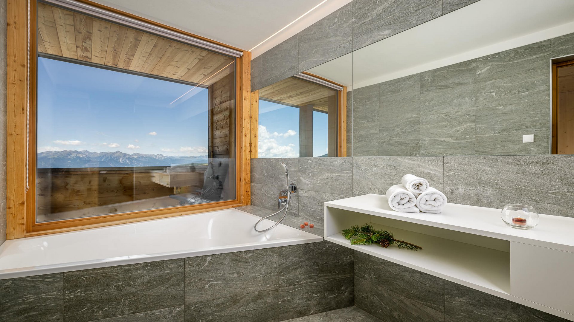 Modernes Badezimmer mit Badewanne und Fenster mit Bergblick