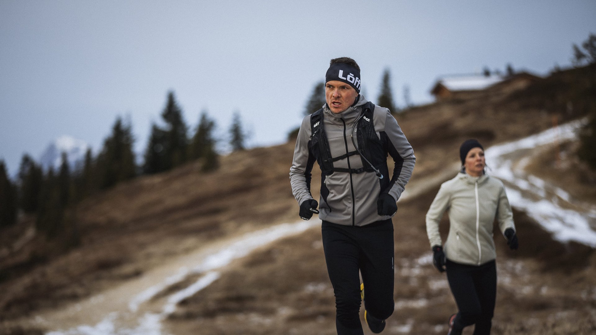 Zwei Personen joggen auf einem Bergweg im Winterkleidung
