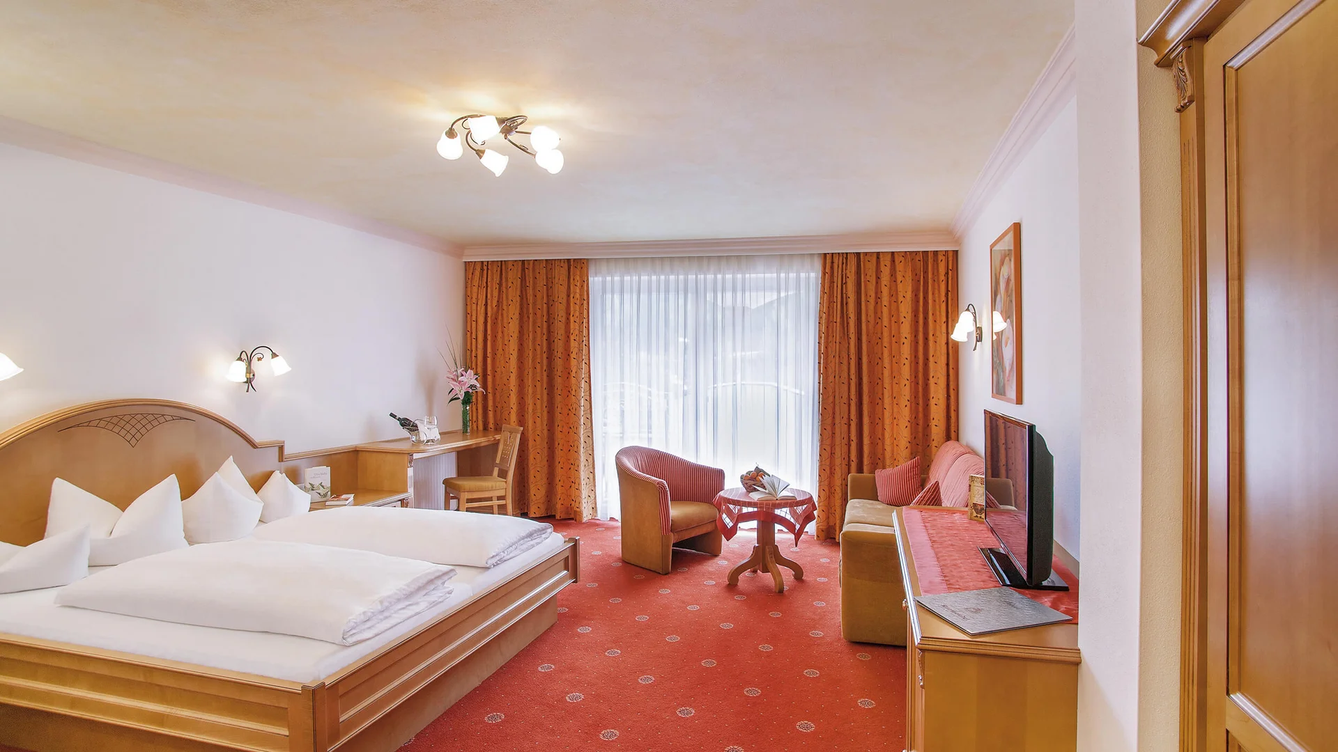 Alpenhotel Karwendel **** © Hotel Karwendel Bernhard Rödlach BetriebsGmbH Gemütliches Hotelzimmer mit Doppelbett, Sitzbereich und TV