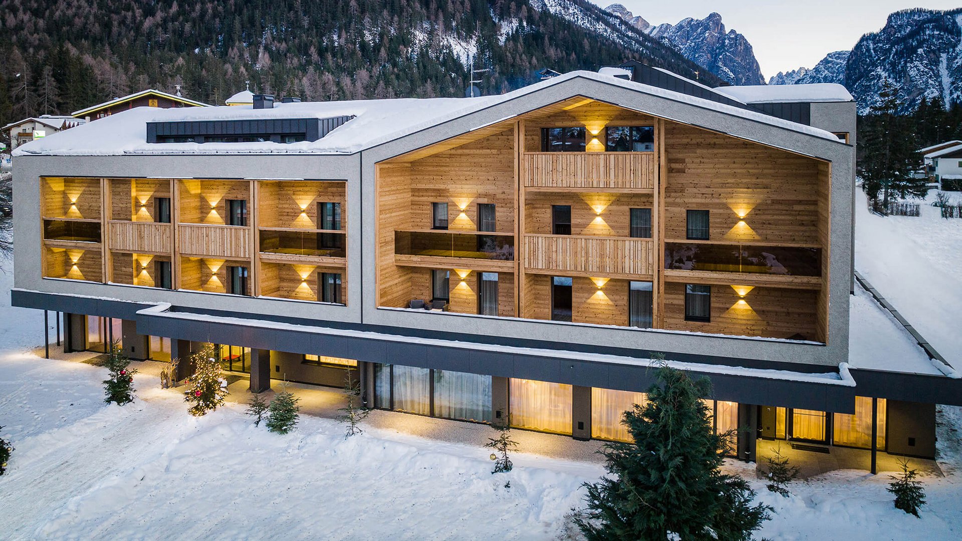 Modernes Hotel in verschneiter Berglandschaft mit beleuchteten Balkonen