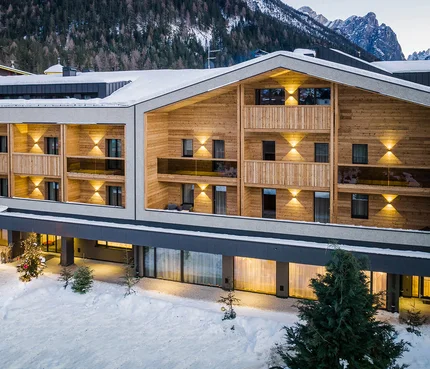 Modernes Hotel in verschneiter Berglandschaft mit beleuchteten Balkonen