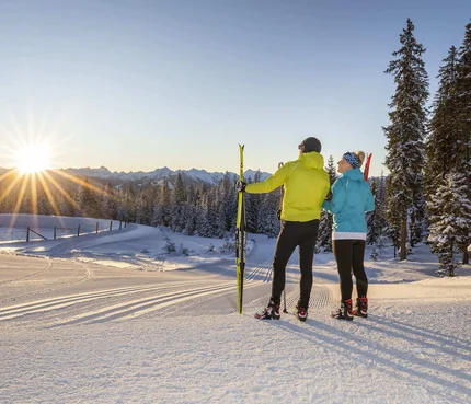Two skiers enjoying the sunset in a snowy mountain landscape